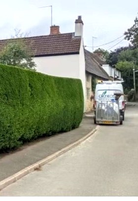 A long, freshly cut roadside hedge with the Alex Ash van parked alongside